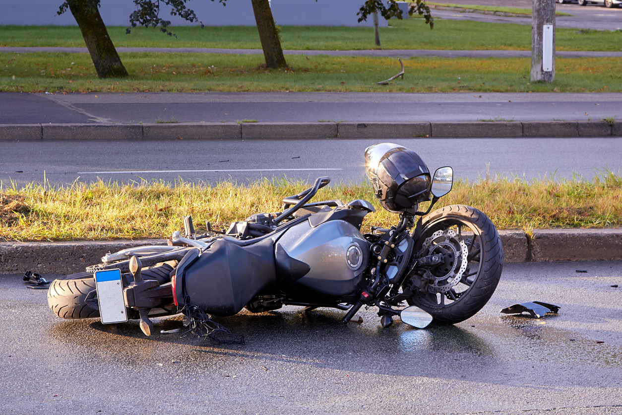 damaged motorcycle laying in the road - motorcycle accident lawyer concept