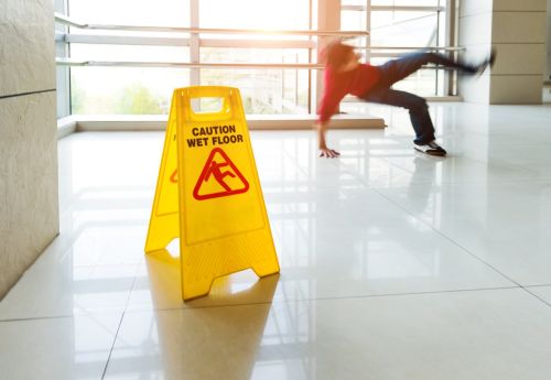 Man slips falling on wet floor next to the wet floor caution sign - Premises liability claim concept