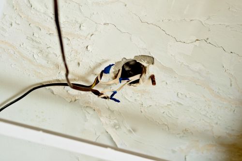 Exposed wires with wire-nuts, dangling from a hole in the ceiling. Building code violation concept