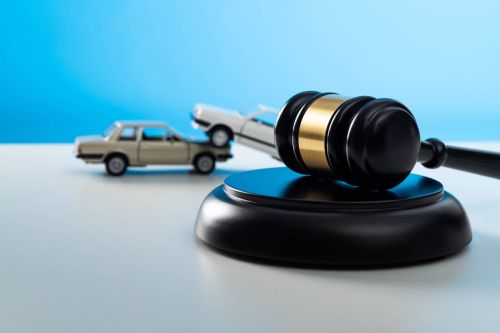 Gavel and model cars crashing on the table. Car accident lawyer concept